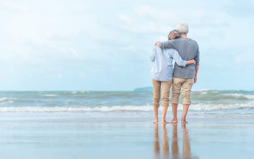 A happy retired couple walking on the beach